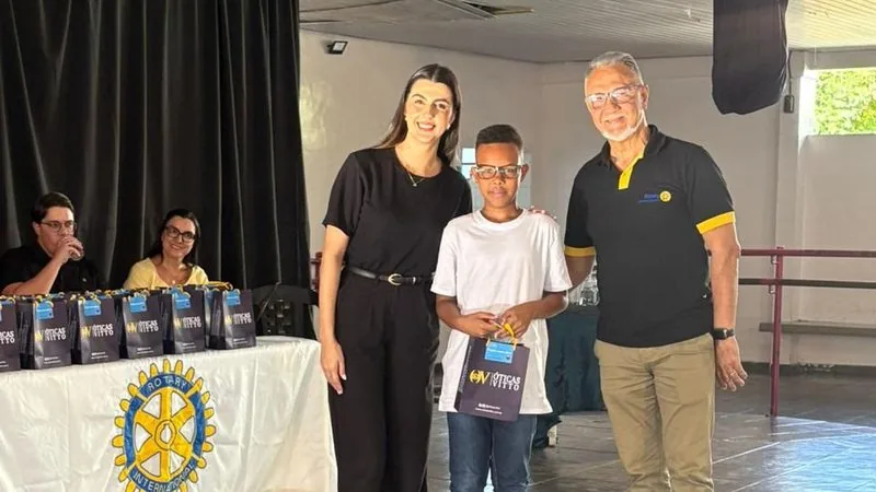 Criança recebendo seus óculos novos das mãos da equipe